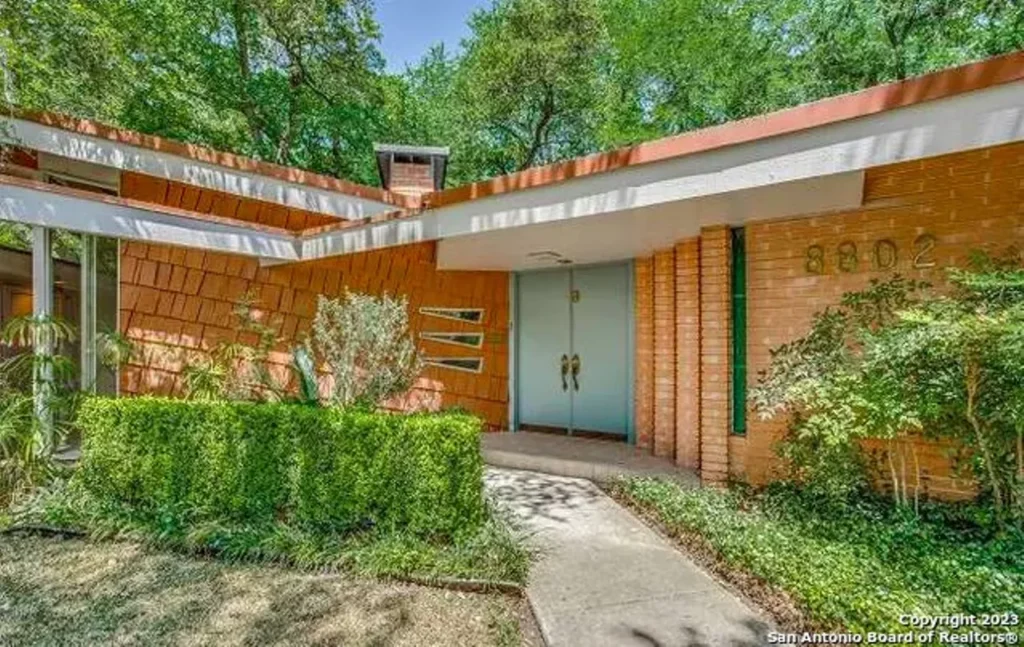 Front view of a mid-century modern house with greenery.